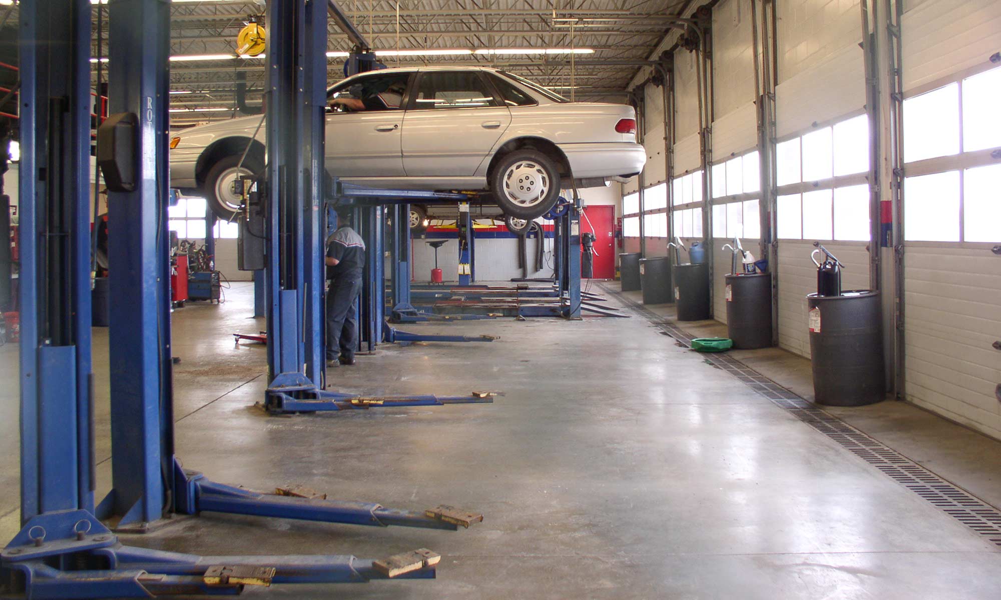 A mechanic working underneath a vehicle that is raised on a lift.