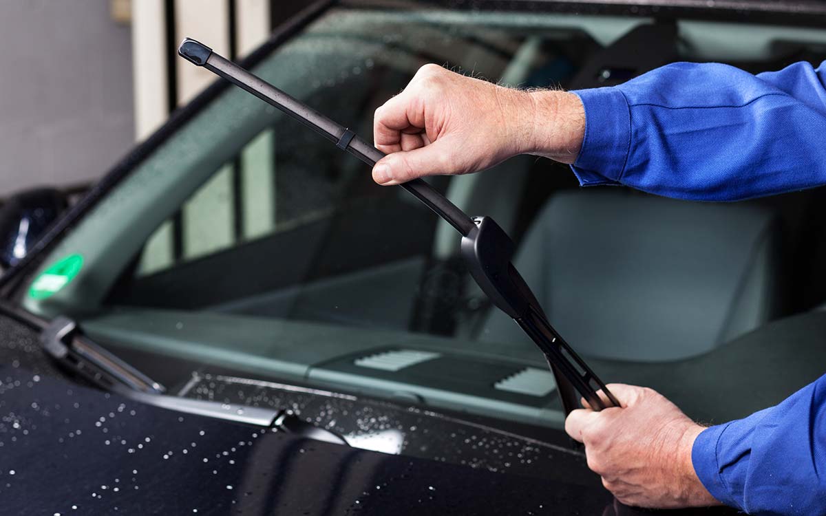 A man changing a car wiper blade.