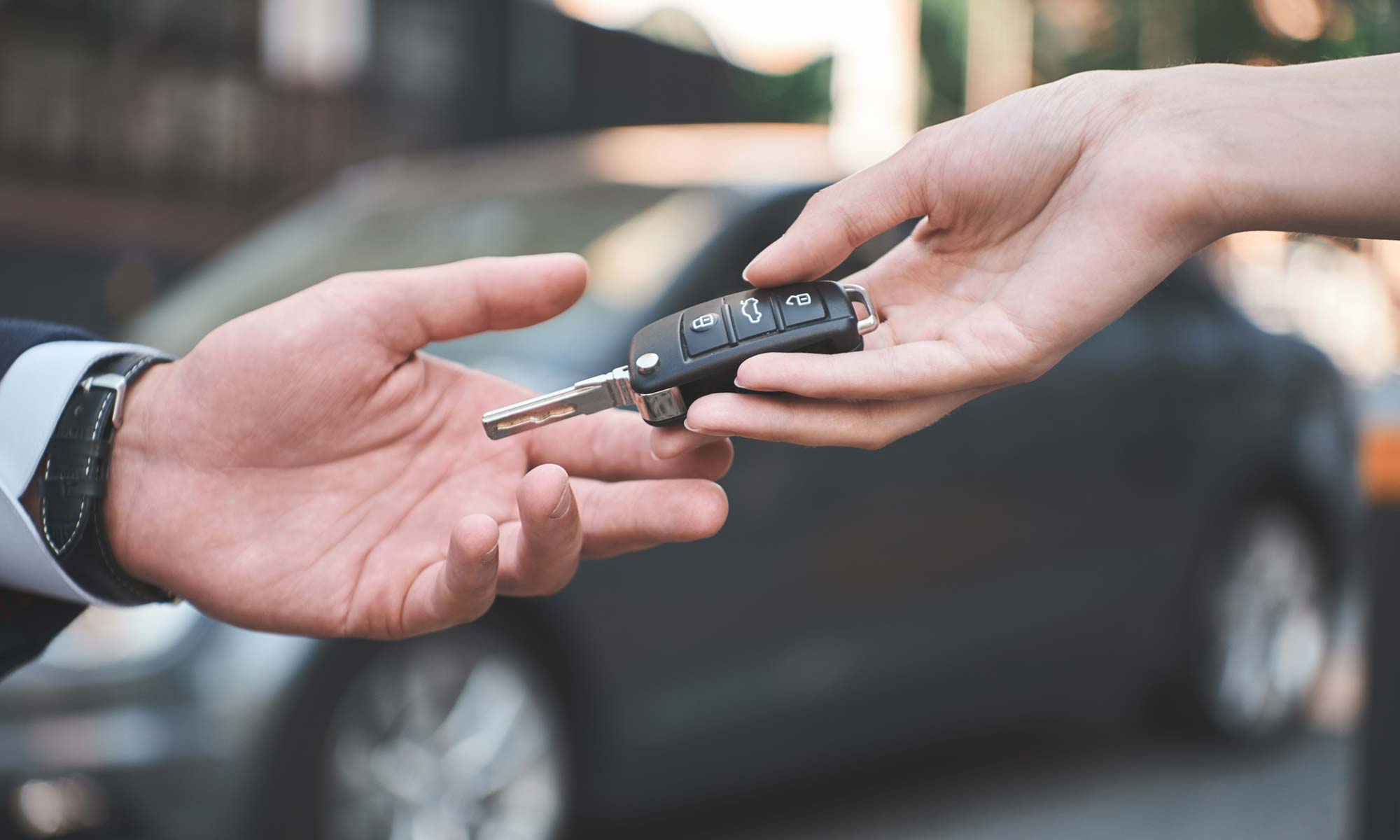 A woman handing the keys to a car to the new owner.