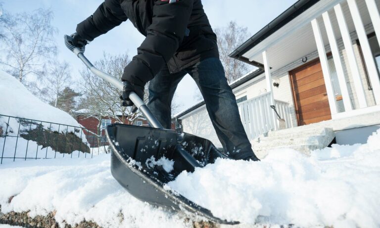 A man shoveling snow outside his home.