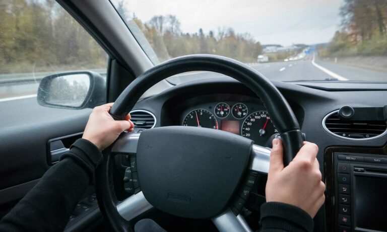 A person's hands on their car's steering wheel.