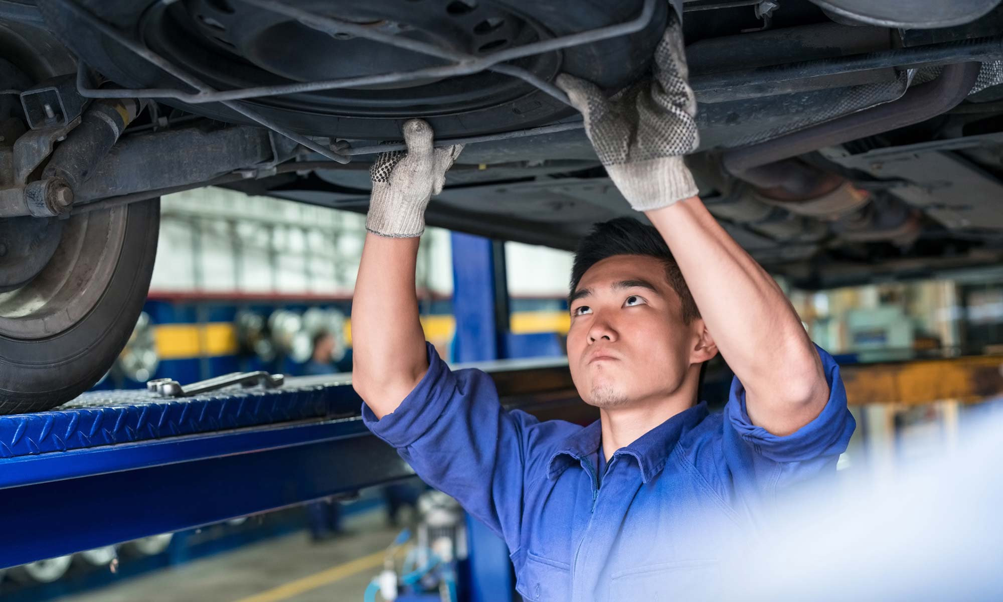 A mechanic checking the undercarriage of a car.