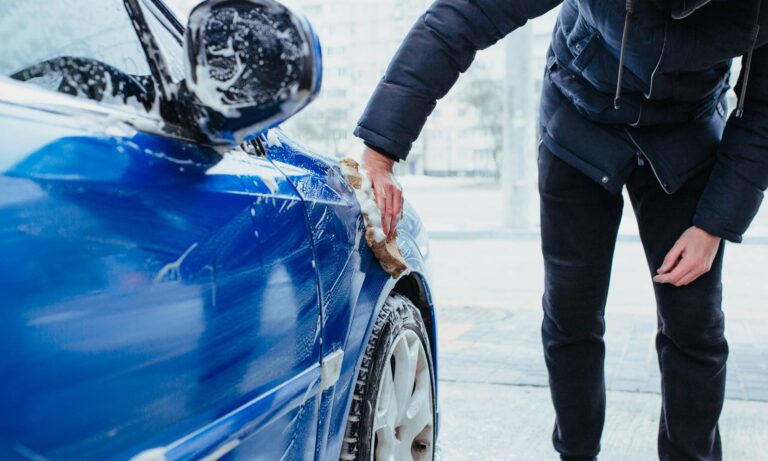 A man washing his car during the wintertime.