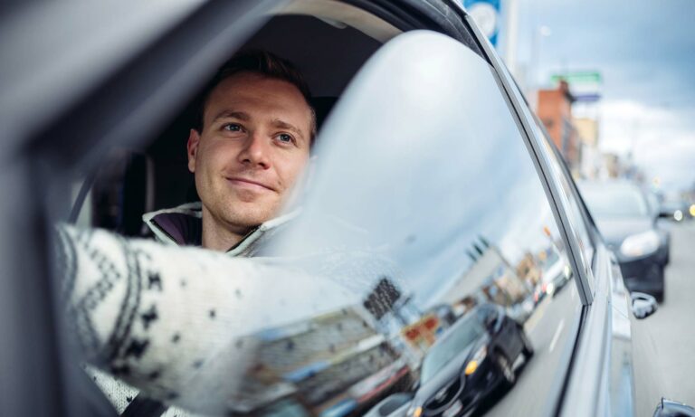 A young man in a winter sweater driving his vehicle.