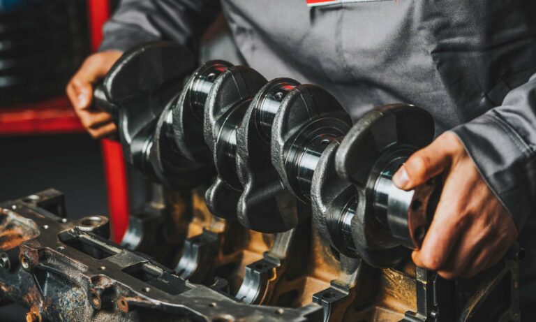 A car's crankshaft being inspected by a car mechanic.