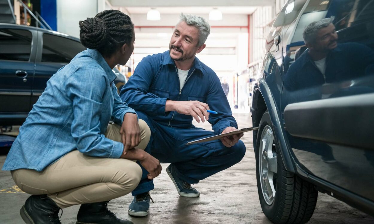 A mechanic speaks with a young woman about her car's tires being covered in her extended warranty.