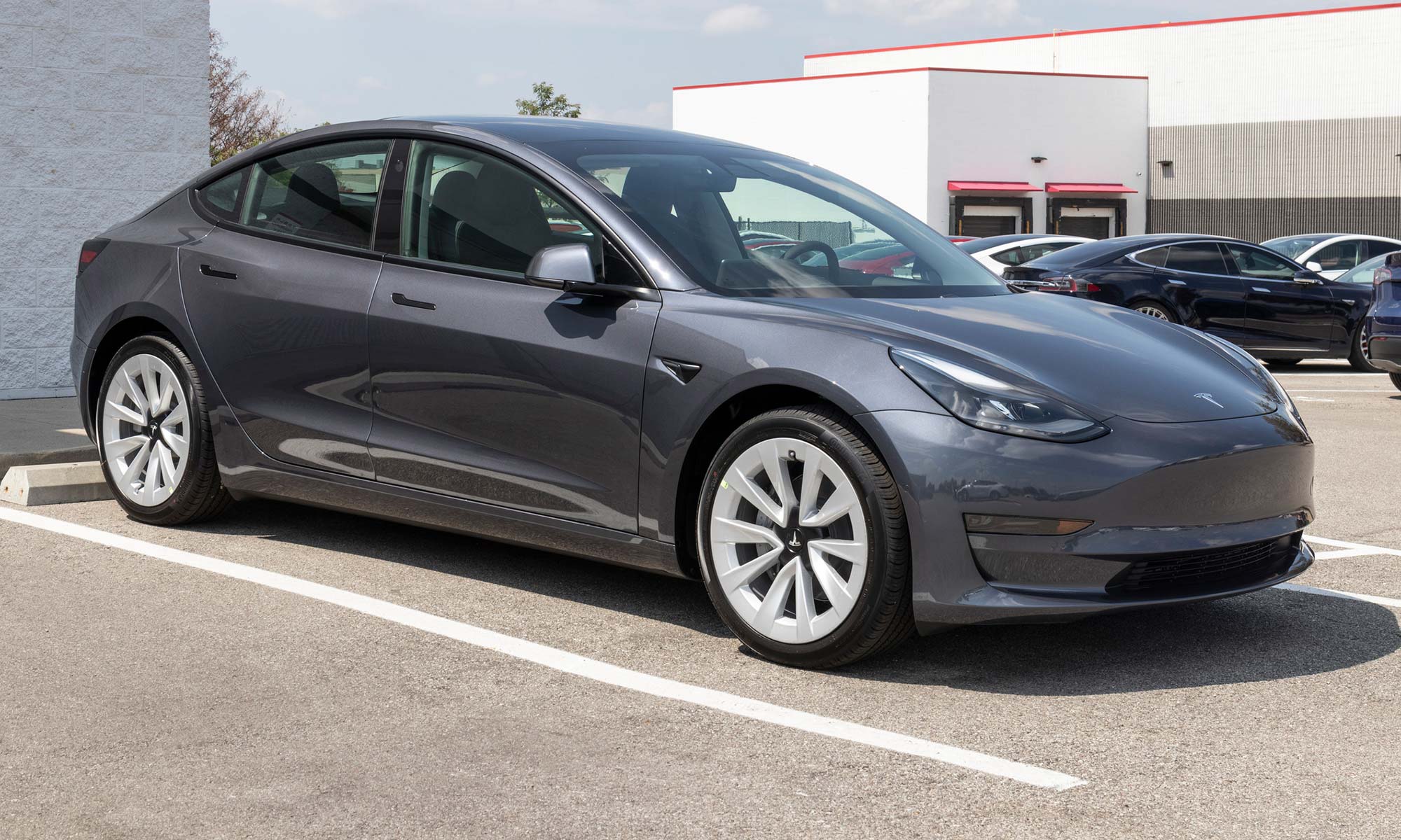 A gray Tesla Model 3 sits in parking space.