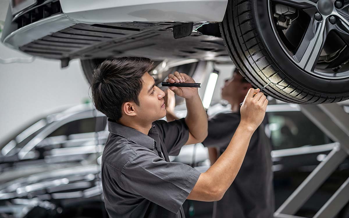 A mechanic checking a vehicle's tire tread during its safety inspection.