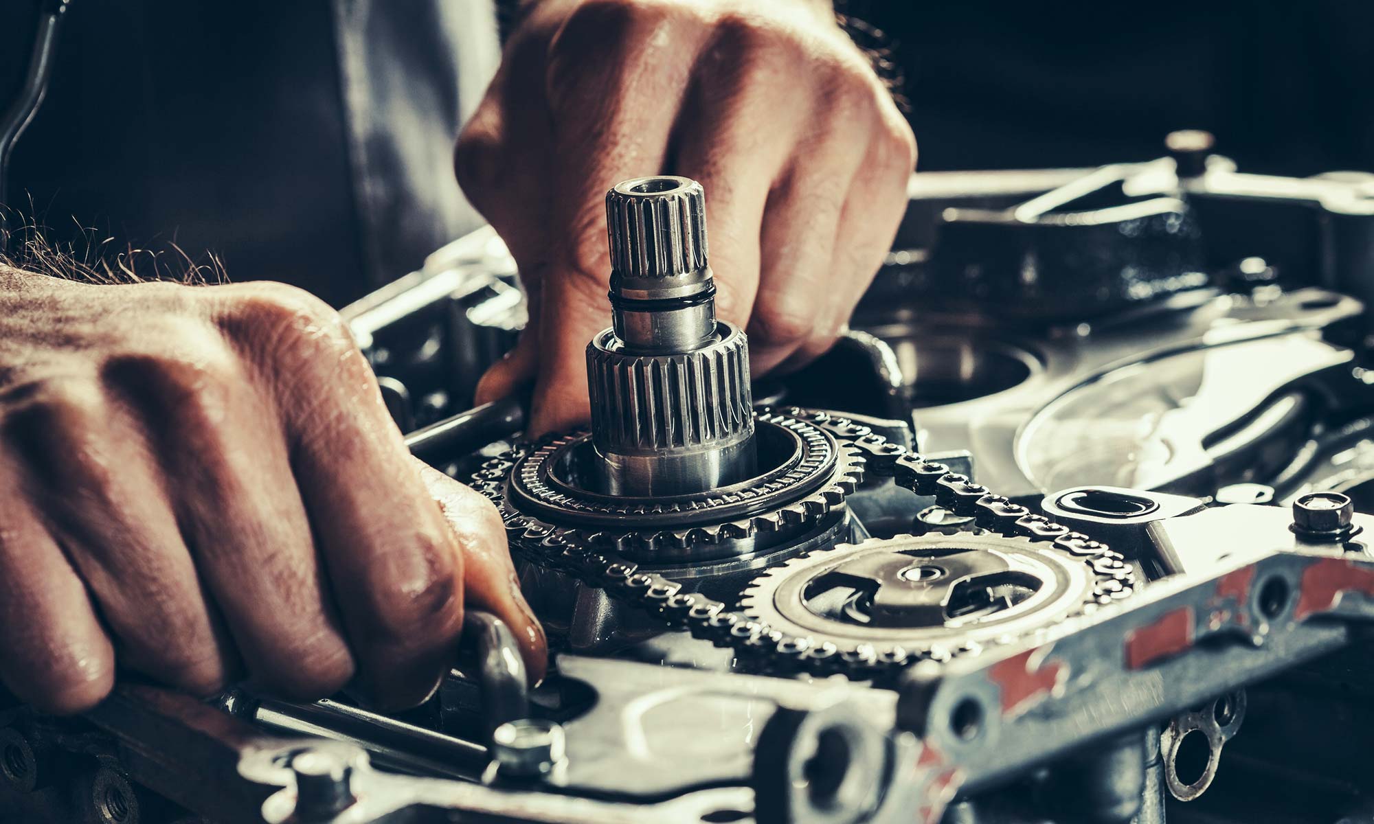 A close-up of a car mechanic fixing a transmission.