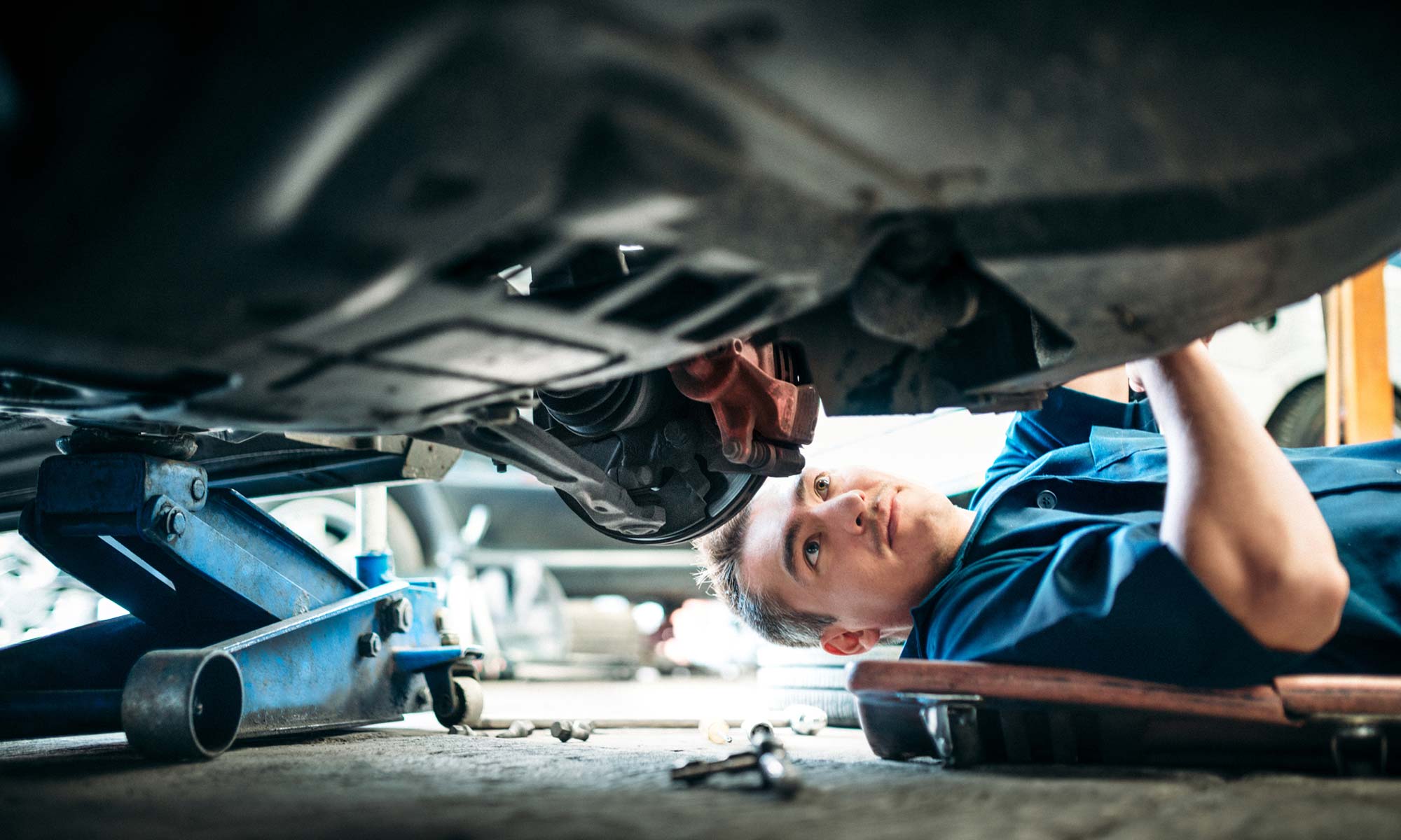 A mechanic checking the undercarriage of a vehicle.