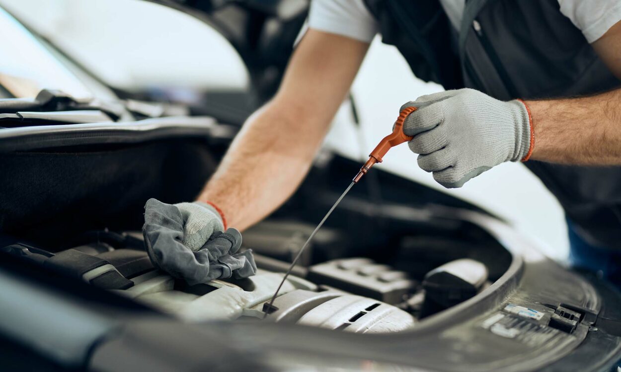 A mechanic checking a car's oil using a dipstick.