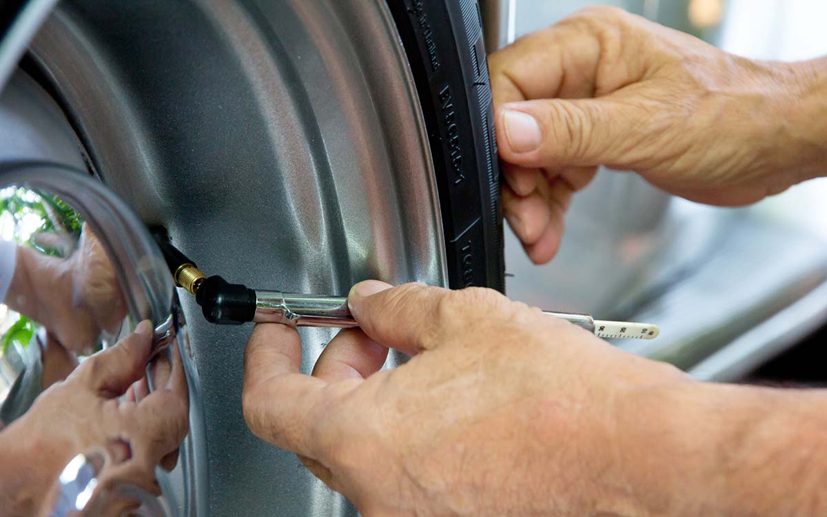 A close up of a person checking their car's tire pressure.