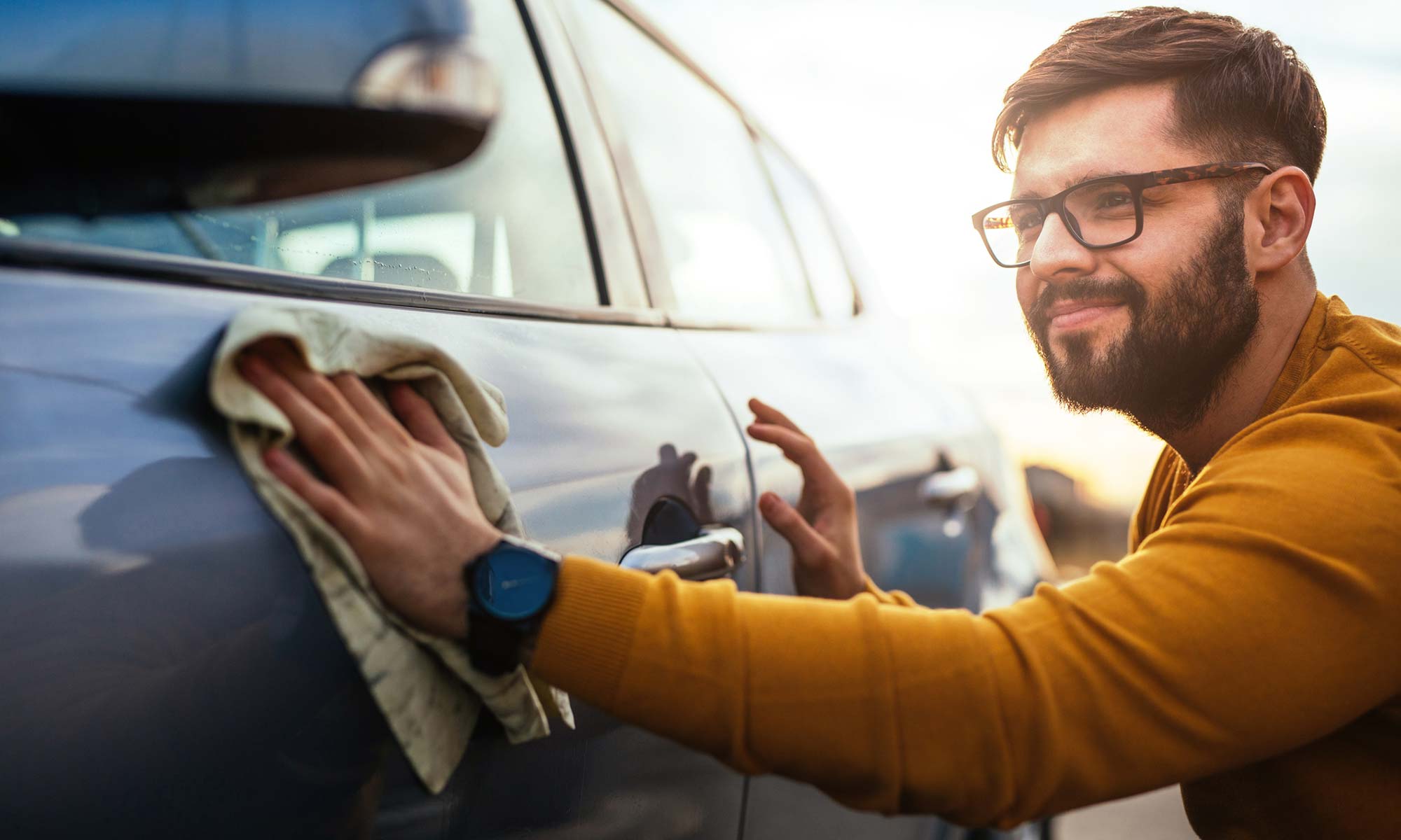 A young man polishing his car.