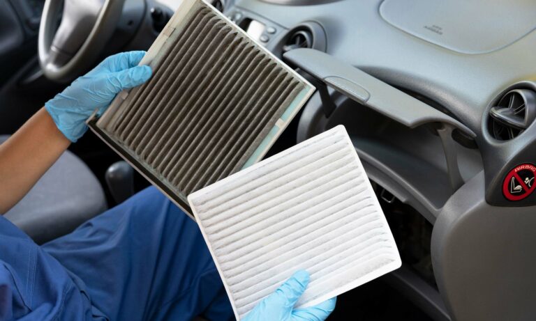 A mechanic holding up an example of a grey, dirty car cabin air filter and a clean, while cabin air filter.