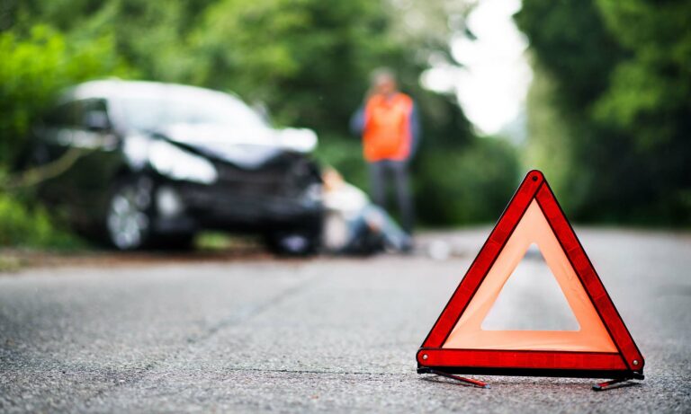 A traffic triangle placed in the road in front of a stalled vehicle.