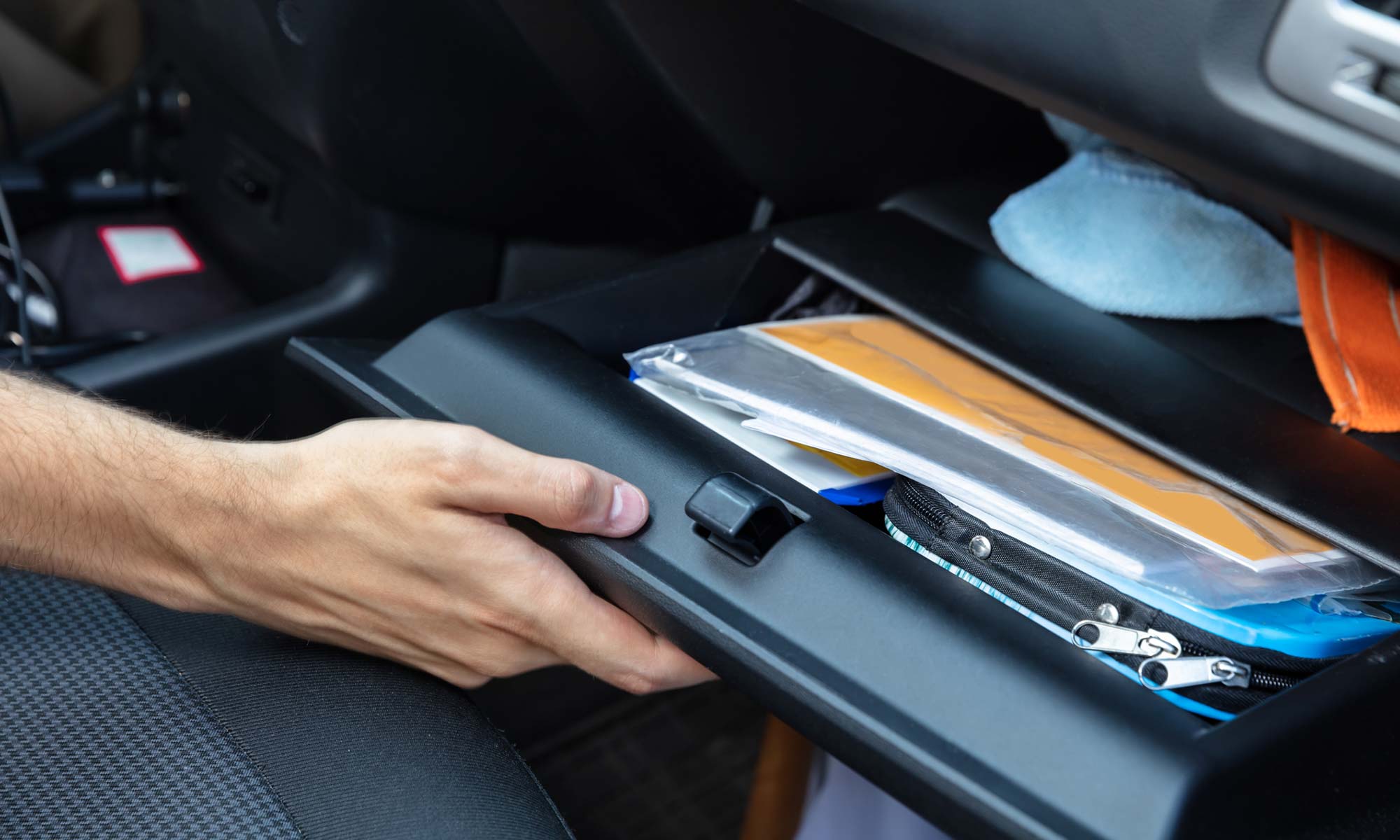 A man opening a car glovebox full of papers.