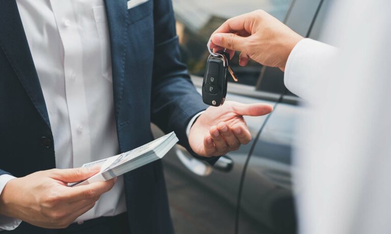 A salesperson hands the keys to a vehicle to a customer.