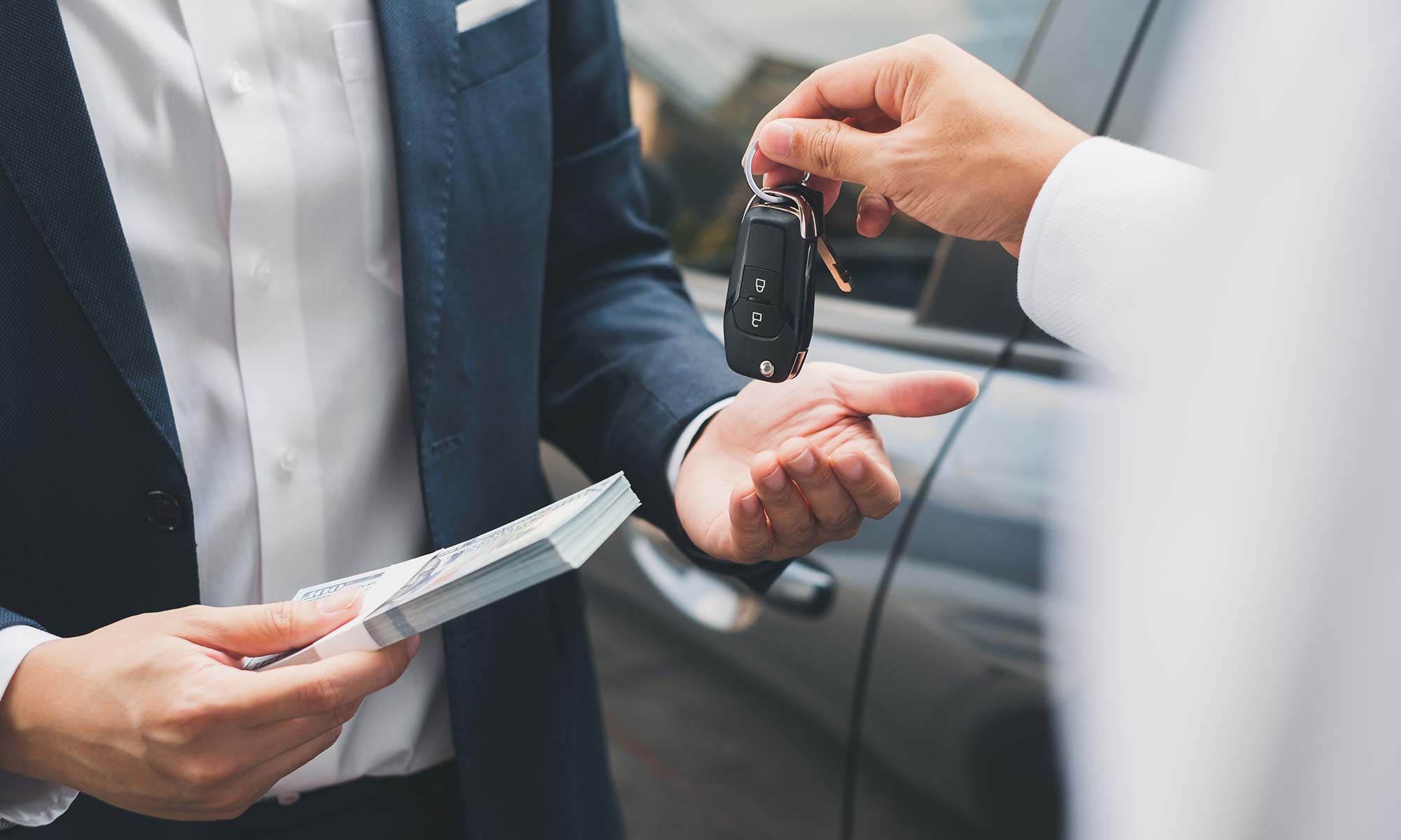 A salesperson hands the keys to a vehicle to a customer.