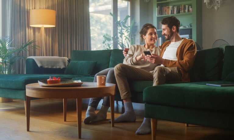 A couple sits on their couch while online shopping for an extended car warranty.