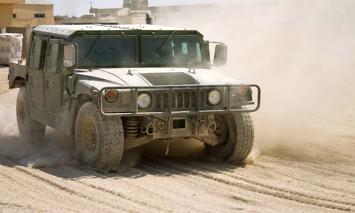 A military HUMVEE driving in the sand.