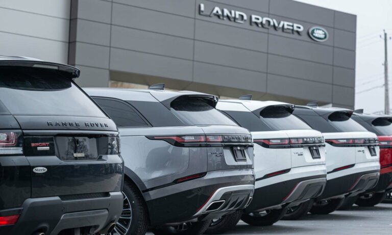 A line of Land Rover vehicles lined up outside a Land Rover dealership.