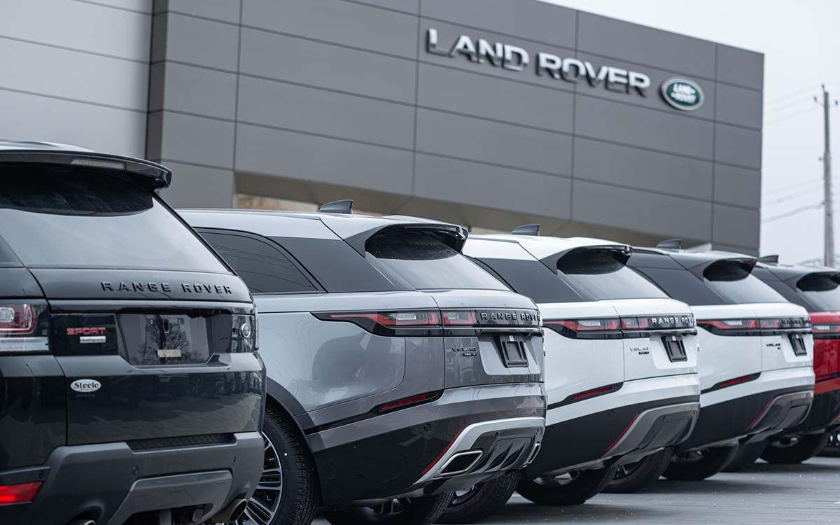 A line of Land Rover vehicles lined up outside a Land Rover dealership.