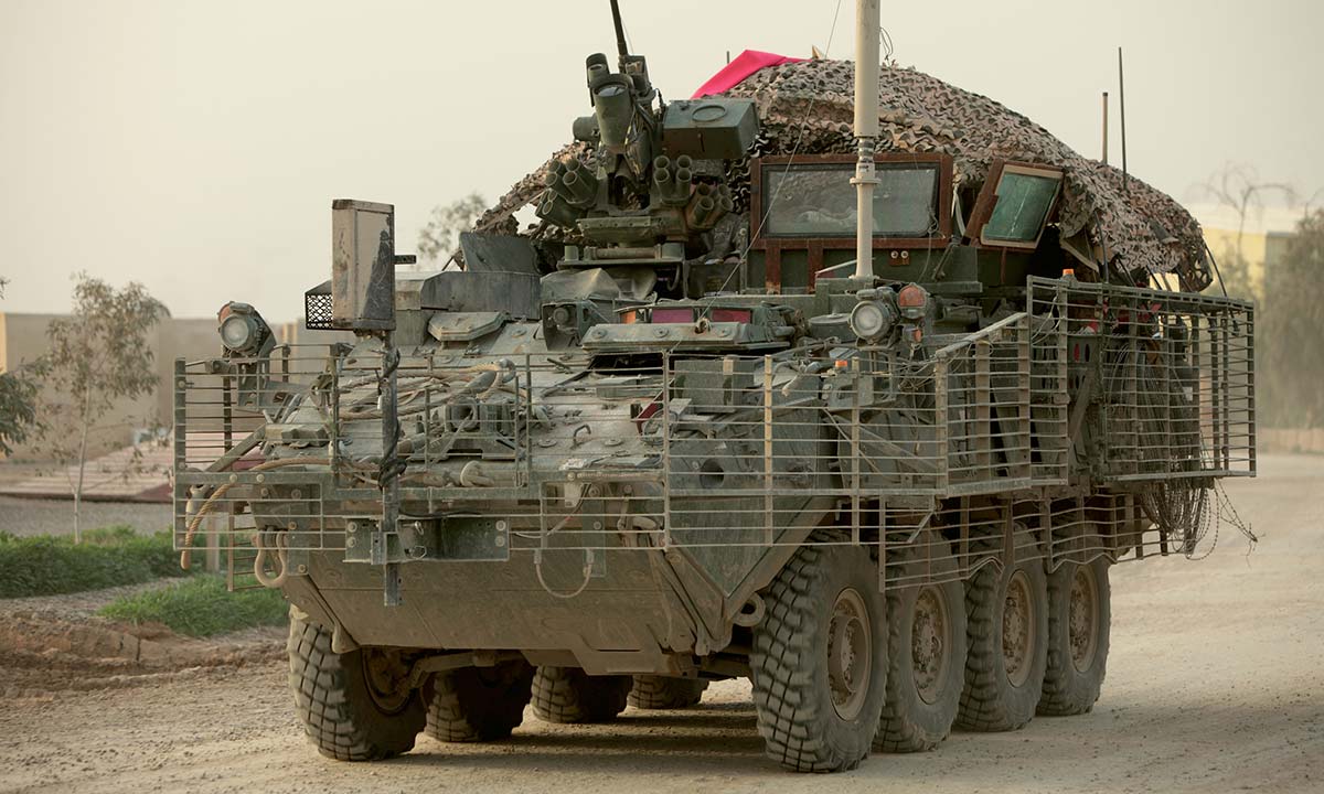 A M1126 Stryker Combat Vehicle driving down a road.