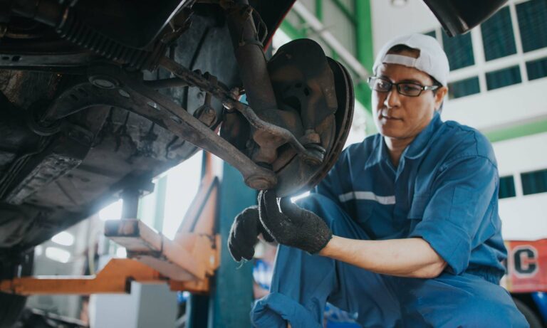 A male car mechanic checking on a vehicle's brakes.