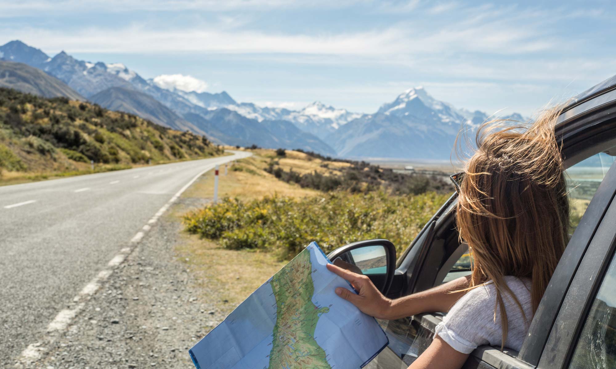 A young woman looking at a map while on a road trip.