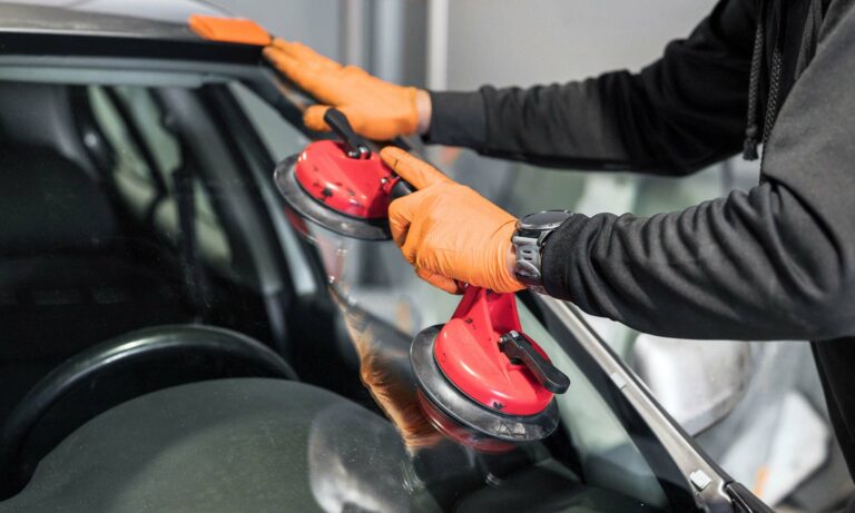 A close up of a repair professional replacing a car's windshield.