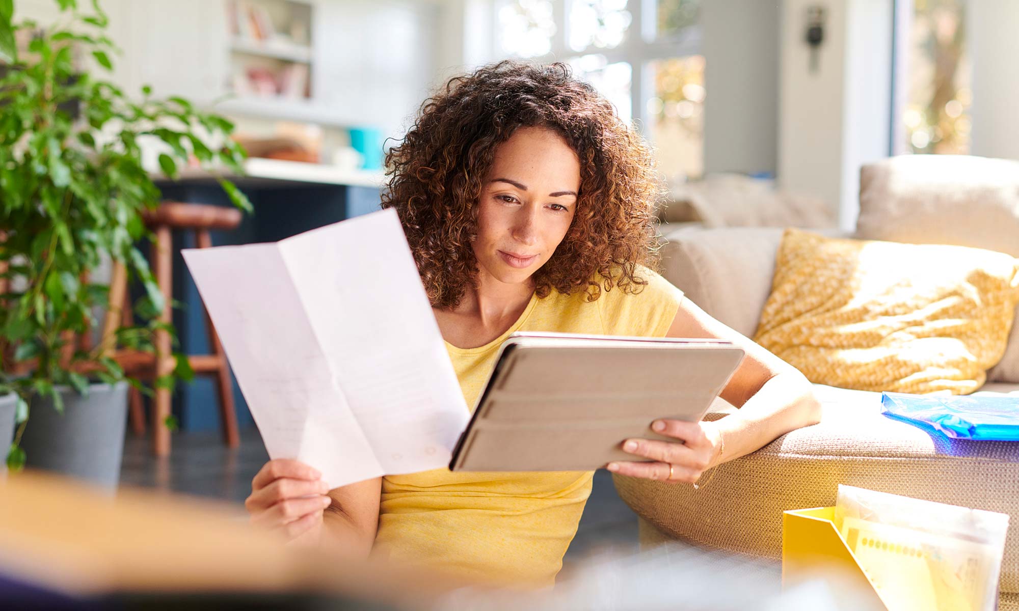 A woman sitting at home on a tablet shopping for an extended car warranty.