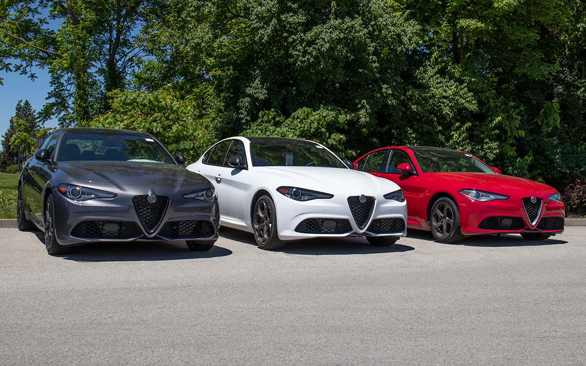 A row of three Alfa Romeo Giulia vehicles in gray, white and red.