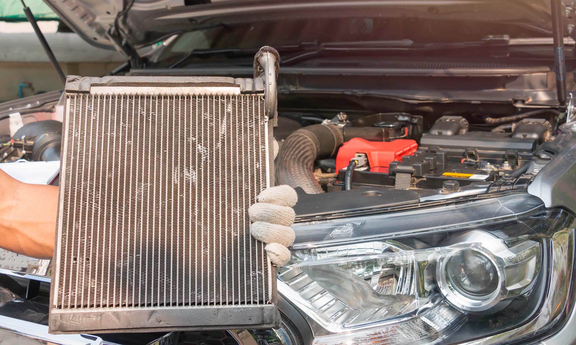 A mechanic holding up a car's radiator.