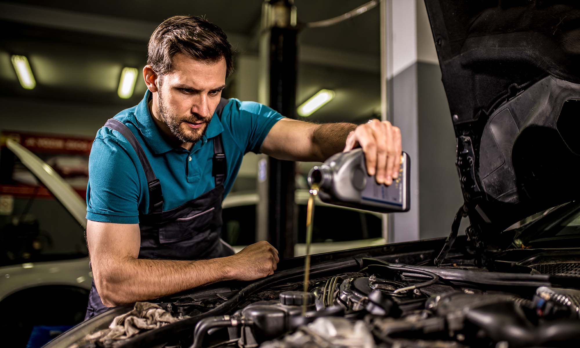 A mechanic pouring new motor oil into a car's engine.