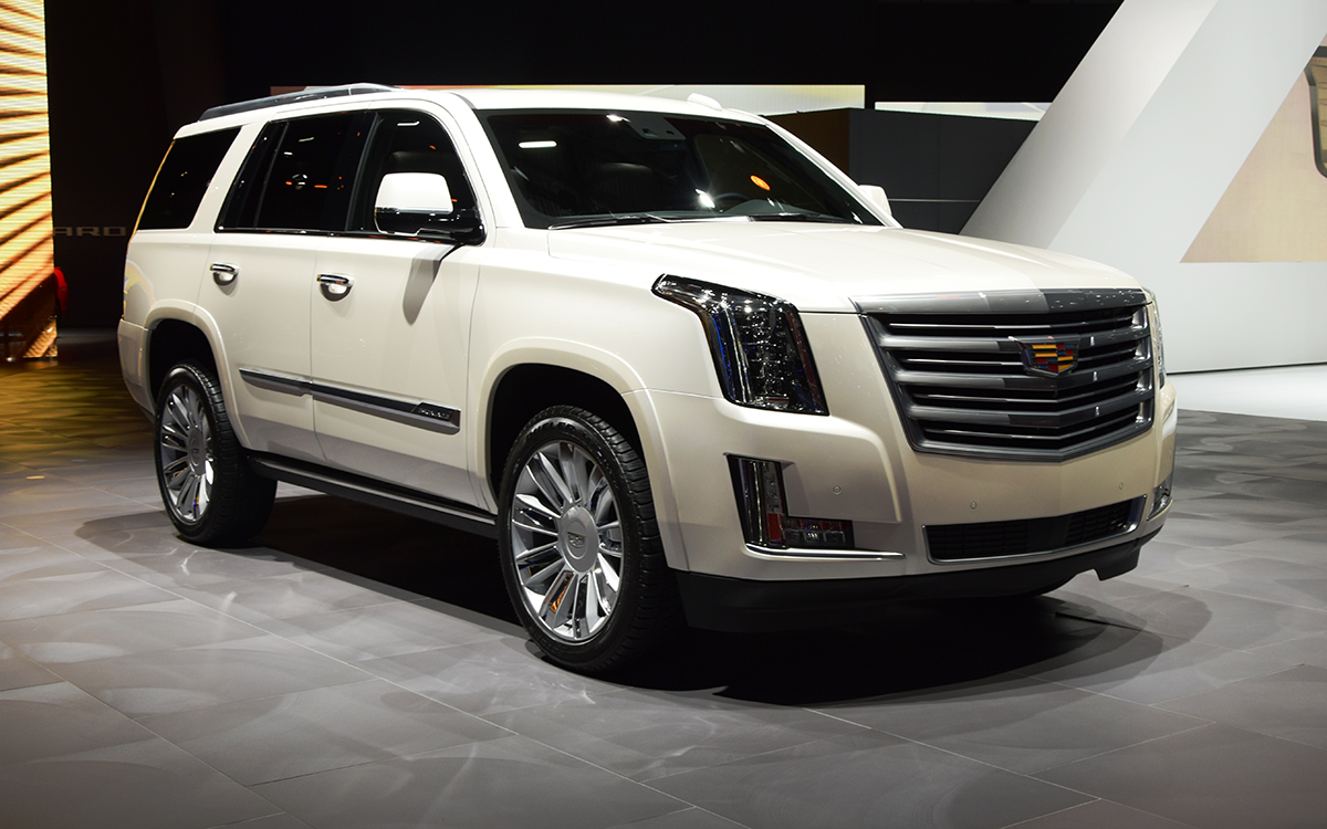 A white 2015 Cadillac Escalade on display at an auto show.