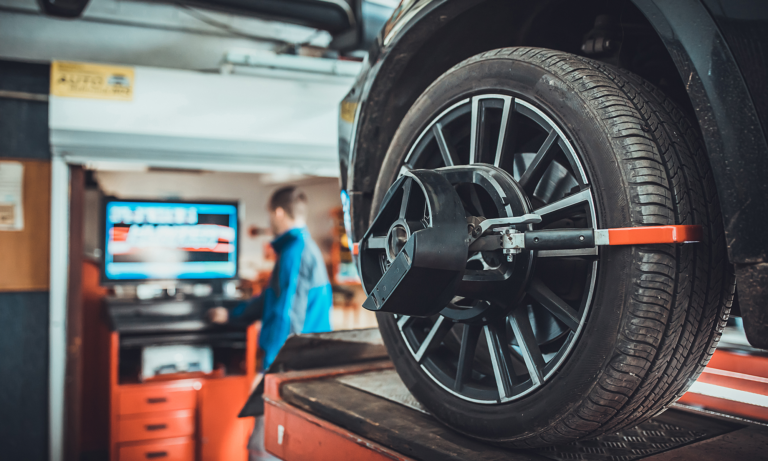 A mechanic checking the wheel alignment of a car at a mechanic shop.