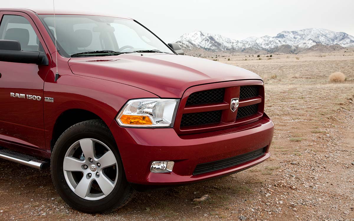 A red Dodge Ram 1500 parked in front of a mountain range.