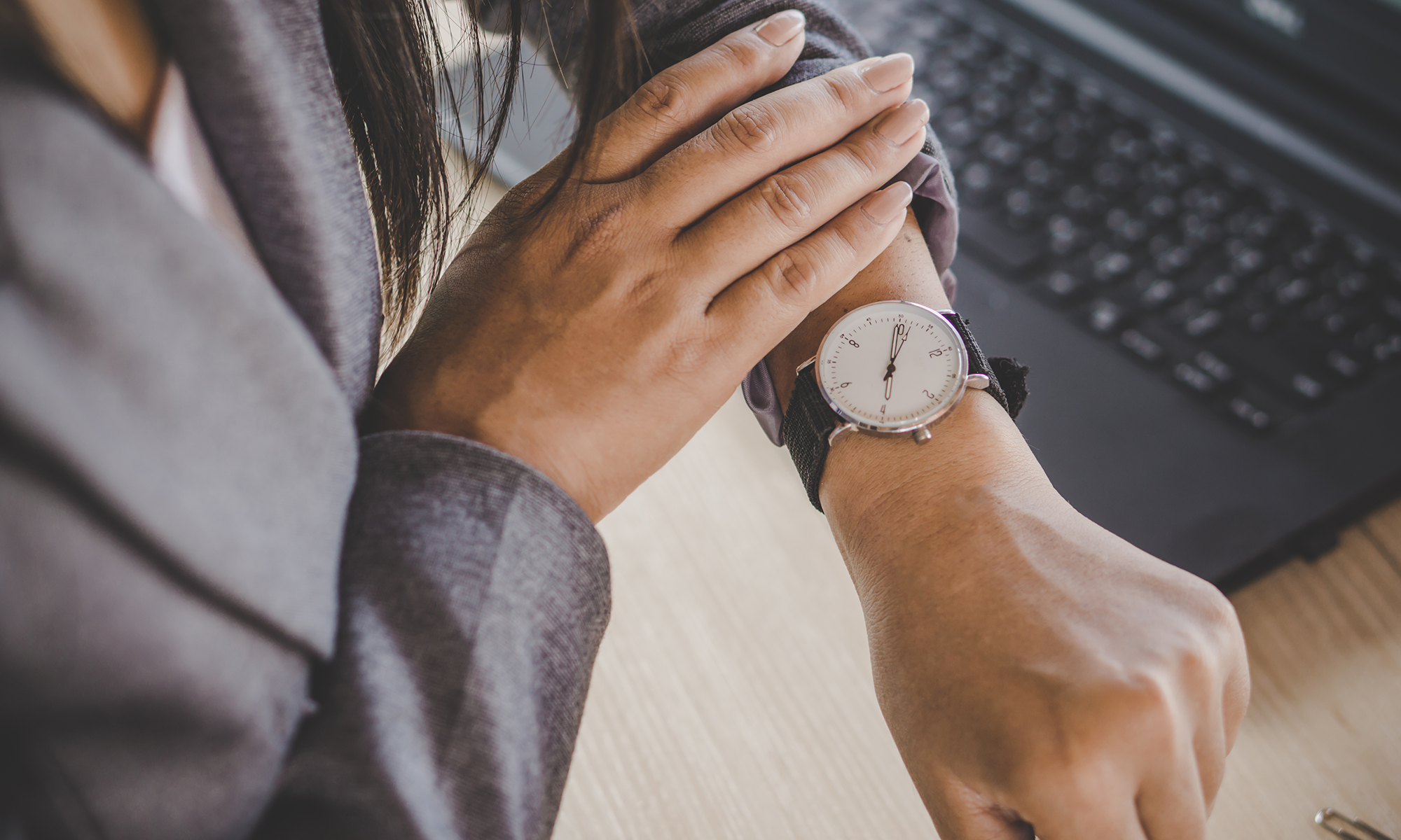 A close up of a woman checking her watch while she waits.