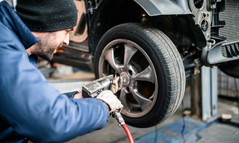 A car mechanic changing a vehicle's tires during a tire rotation.