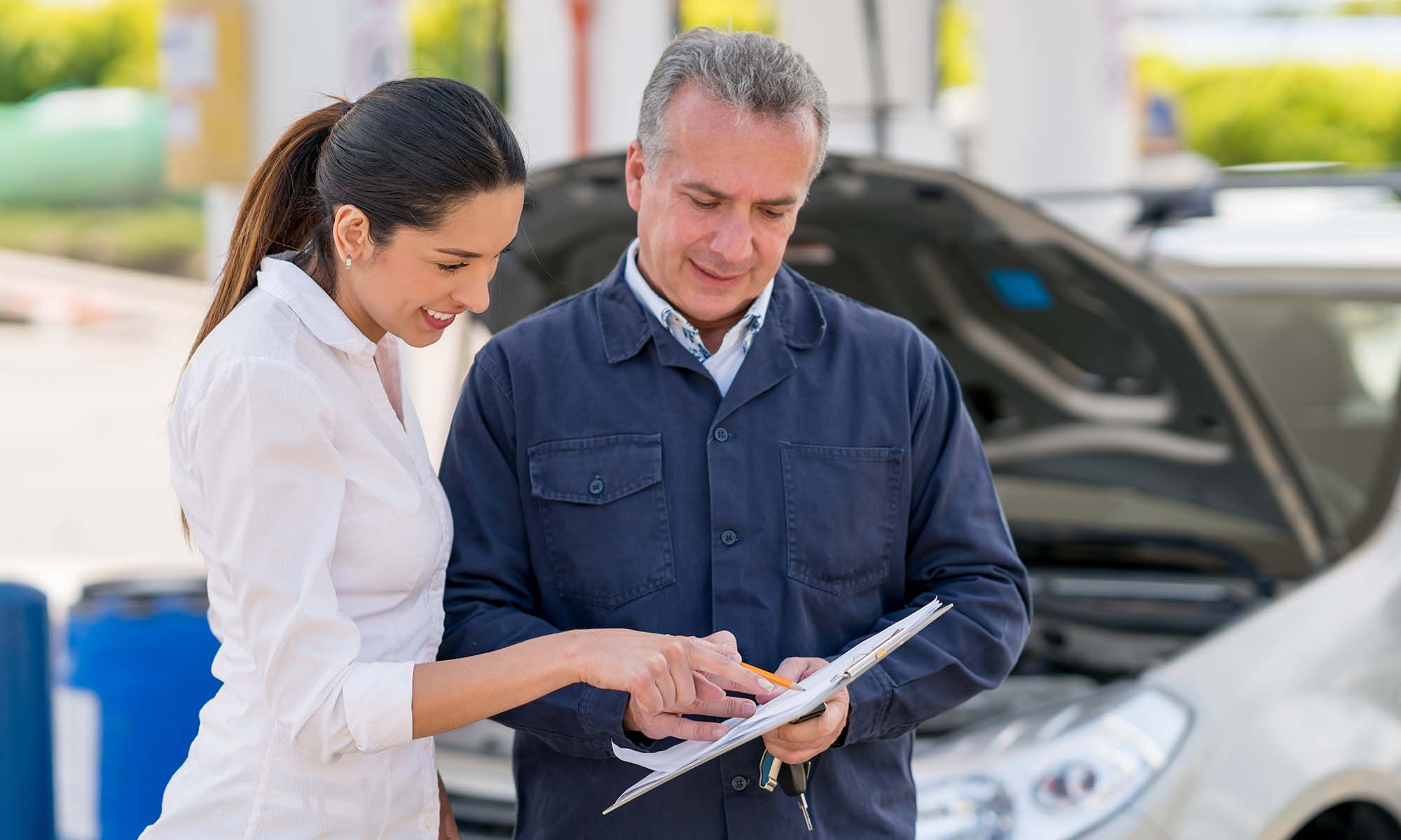 A young woman checking her vehicle's service contract with a mehanic.