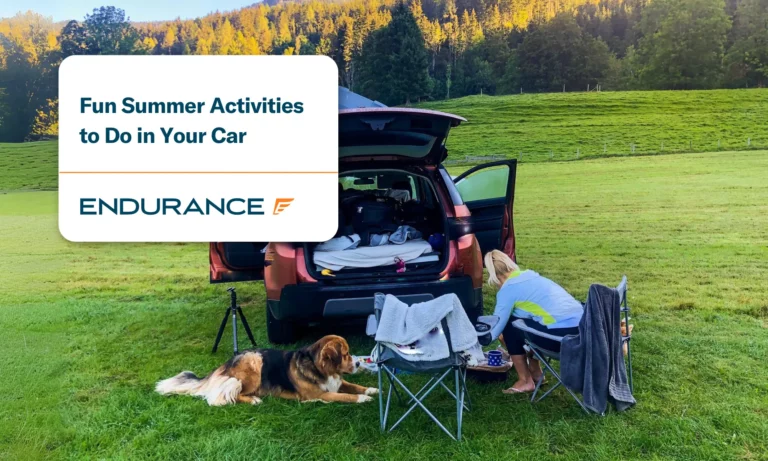 A young women and her dog having a small picnic out of the trunk of her car parked in an open field.