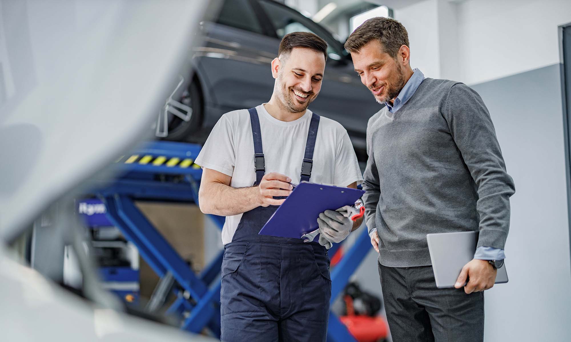 A car mechanic goes over a chart of repairs with their customer.