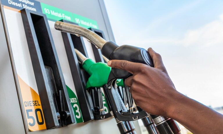 A person removing the diesel fuel nozzle at a gas station fuel pump.