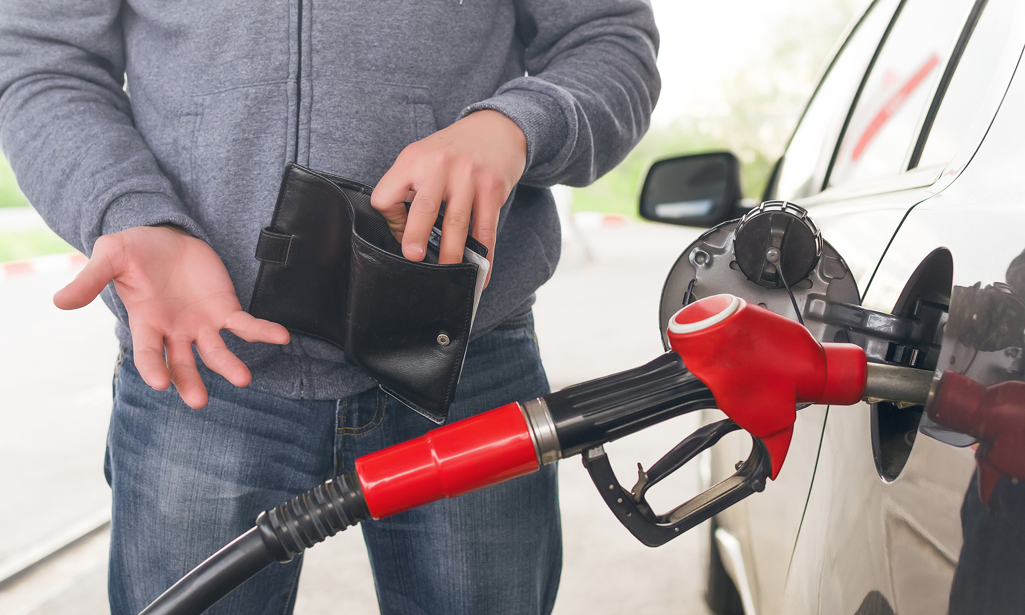 A man holding up an empty wallet while pumping gas for his car. But like having an Endurance Warranty auto protection plan to help save against repair bills, knowing how to improve your cars mpg can also help you save.