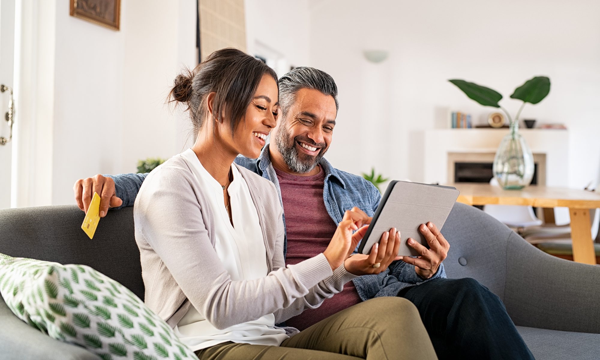 A couple sits on their couch and compares car warranties from CarMax, Carvana and Endurance Warranty.