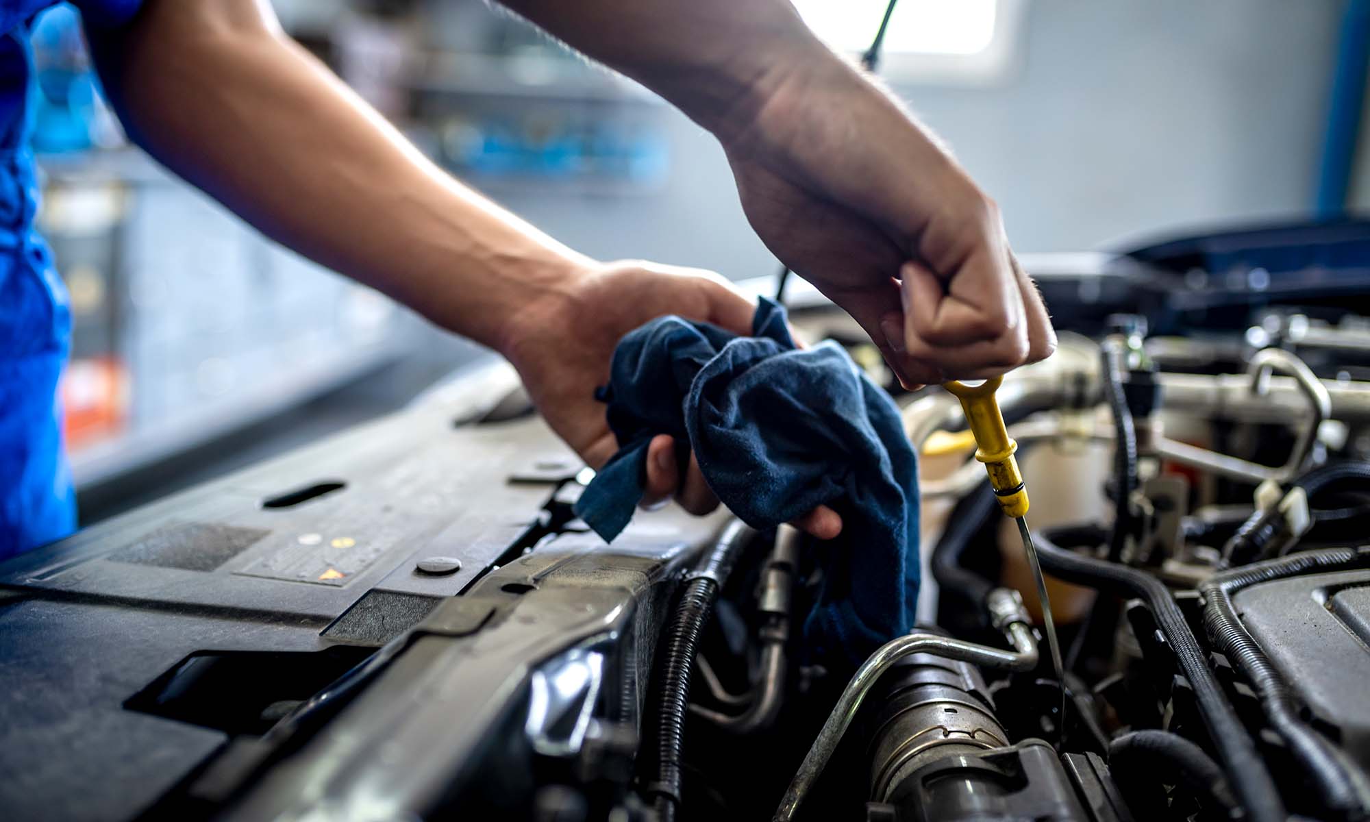 A person checking their car's oil using an oil dipstick.