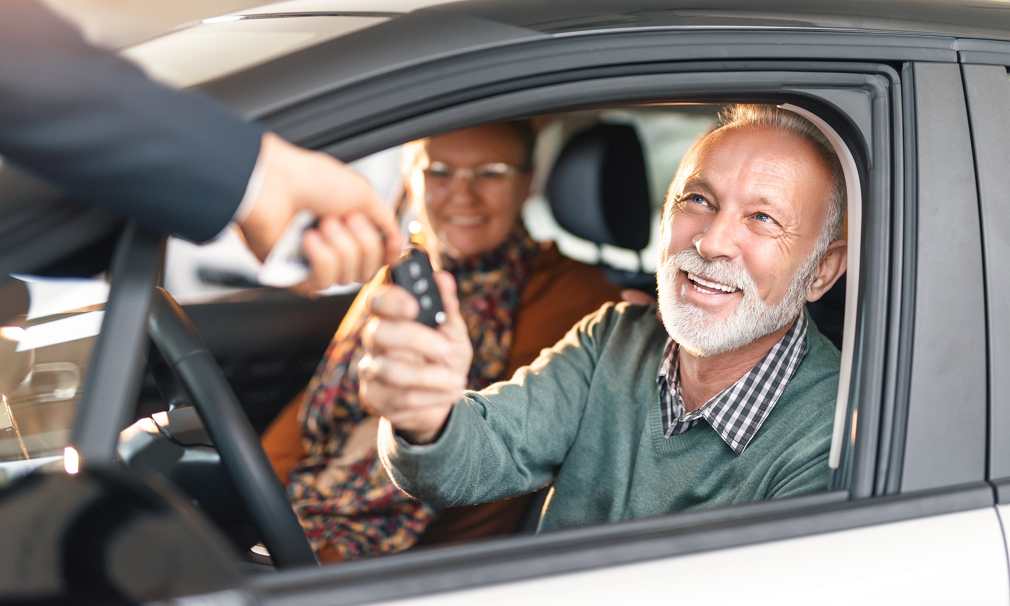 An older couple is handed the keys to their brand new car.