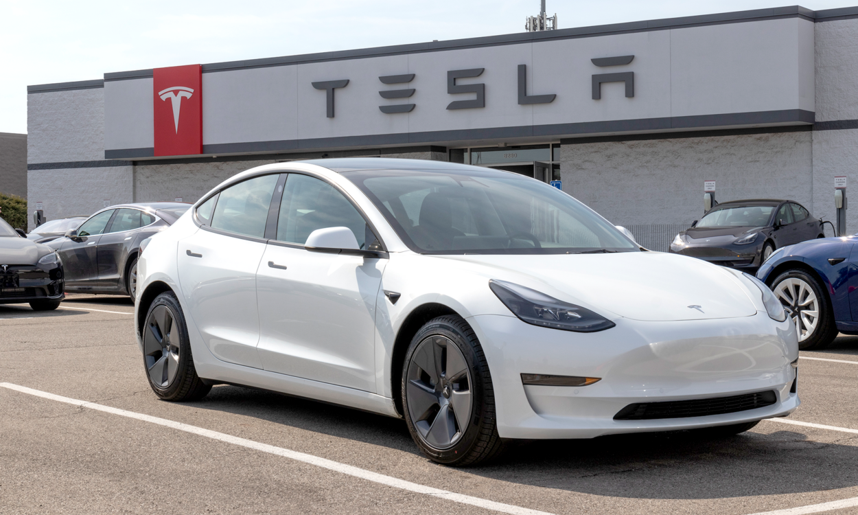 A white Tesla vehicle sitting in the lot of a Tesla dealership.