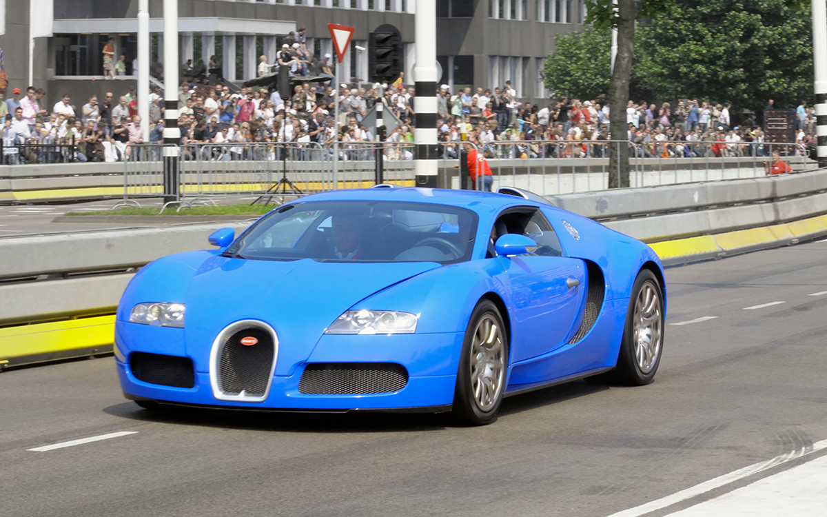 A blue Bugatti Veyron racing down raceway.