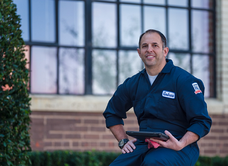 Auto Expert Andrew Giorgi dressed in his mechanic coveralls with a tablet in his hand